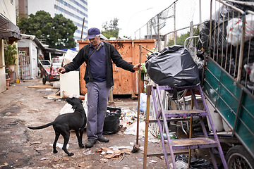 Image showing Man, worker and cleaning of trash for waste management in junkyard with broom or playing with dog. Person, working or smile by dumpster site for scrap, recycling or garbage in neighborhood for litter
