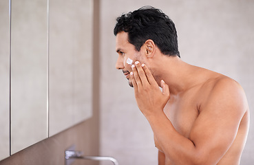 Image showing skincare, face cream and man in a bathroom mirror with lotion, application or morning routine at home. Beauty, sunscreen and profile of male person in a house with skin, cosmetics or facial treatment