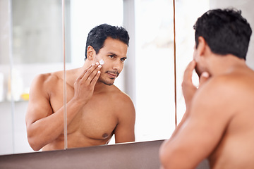 Image showing Man, mirror and cream in bathroom for skincare, cosmetic treatment and hygiene in reflection for routine. Topless, handsome person with smile and touch face for groom, wellness product and fresh