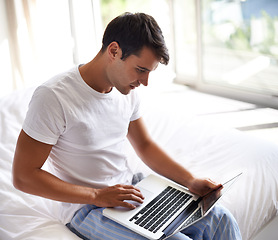 Image showing Man, bed and laptop for communication, internet and technology in bedroom, home and apartment in morning time. Male person, student and computer on social media, browsing and online connectivity