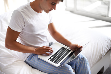 Image showing Man, happy and laptop in bedroom, scroll and entertainment in pajamas and morning routine. Male person, browse and social media with technology, bed and smile in sleepwear at home for relaxation