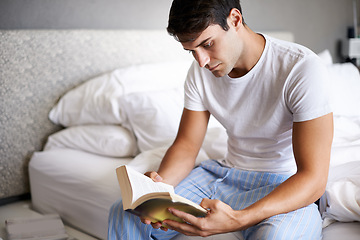 Image showing Man, reading and pajamas for morning, routine and book in bedroom for wellness and literature for class. Male person, hobby and student for relaxation, leisure and novel for home free time in house