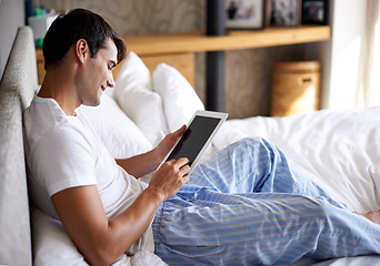 Image showing Man, smile and bed with tablet for communication, internet and technology in bedroom, home and apartment in morning time. Male person, student and digital pad on social media, browsing and online