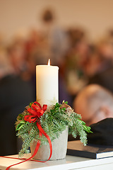 Image showing Christmas, religion and candle with mistletoe in church, bible and holy book or gospel on table for worship to God. Spiritual, faith and closeup of wax light to help Christian to pray for heaven