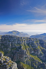 Image showing Mountains, landscape and clouds in sky for travel, hiking or eco friendly tourism by ocean or sea on horizon. Aerial view of environment, nature and rock texture or mockup in Cape Town, South Africa