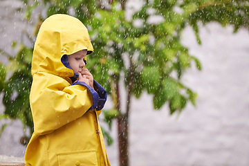 Image showing Child, jacket and rain in outdoor for fashion, play and walk to kindergarten in cold. Boy, cute and adorable kid with clothes in water droplets in garden or backyard for childhood and innocent