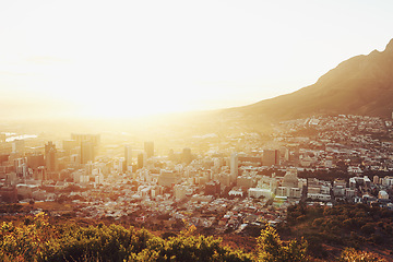 Image showing Sun, top view of city with landscape and mountains, buildings and architecture with nature outdoor. Flare, natural light and urban development background for property, horizon or skyline with travel