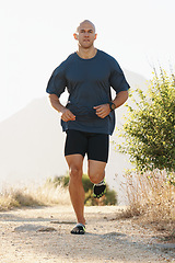 Image showing Fitness, running and man on path in mountain for health, wellness and strong body development. Workout, exercise and runner on road in nature for marathon training, performance and morning challenge.