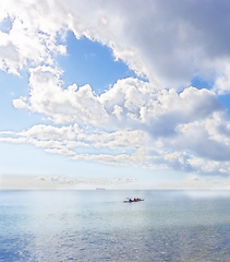 Image showing Ocean, blue sky and people on kayak for adventure, sports and travel on natural background or landscape. Sea, fresh air and clouds with calm water, boat on journey and recreation activity for holiday