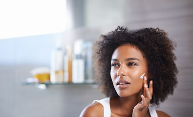 Image showing African woman, skincare and facial cream with smile, wellness or afro in home bathroom for morning routine. Girl, person and serum with cosmetics, beauty or transformation with self care in apartment
