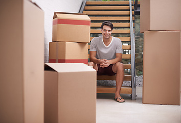 Image showing Man, moving and portrait in new house by stairs with boxes, fresh start or investment in real estate. Person, cardboard and package on steps in apartment, home or happy for rent, mortgage or property