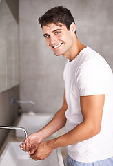 Image showing Portrait, smile and man washing hands in bathroom of home for morning grooming, hydration or hygiene. Cleaning, water and wellness with happy young person in apartment for self care at basin