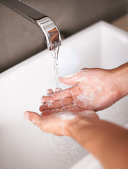 Image showing Person, hands and soap with water for hygiene, cleaning or germ and bacteria removal in bathroom at home. Closeup of tap or faucet for disinfection, washing or rinsing in cleanliness by sink at house