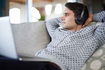 Image showing Laptop, thinking and man with headphones in home to relax or listening to sound of radio podcast on sofa. Computer, music and dream of serious person in lounge for social media and streaming audio