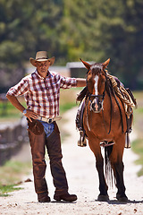 Image showing Cowboy, horse and portrait on farm in country and rodeo person on western ranch in nature. Trainer, confident and face with strong stallion of american quarter and outdoor with healthy thoroughbred