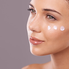 Image showing Face, cream and thinking of skincare with woman in studio, moisturizer and dermatology for wellness on purple background. Skin health, cosmetic product with sunscreen or lotion dots, facial or mask