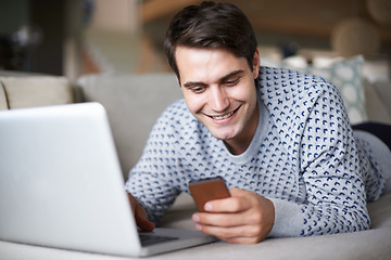 Image showing Man, home and sofa on smartphone with laptop, happy and smile for social media post and entertainment. Male person, living room and couch on internet for streaming service or website for news update