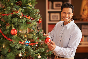 Image showing Happy man, portrait and Christmas tree with decor or bauble for festive, celebration or December at home. Male person with smile, ornament or interior decoration for traditional season or new year