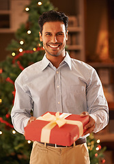 Image showing Happy man, portrait and Christmas tree with gift box for present, festive or December celebration at home. Male person with smile for season of giving, thank you or tradition in living room at house