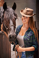 Image showing Horse, farm and ranch with young woman in barn or stable for work in agriculture or sustainability. Cowgirl, texas or western and happy animal farmer or owner with stallion for equestrian training