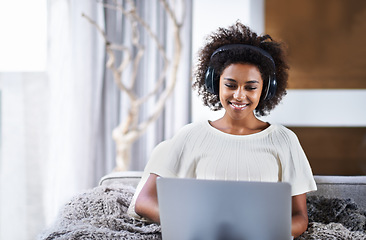 Image showing Laptop, music and smile with afro black woman on sofa in living room of home for social media browsing. Computer, streaming and headphones with happy young person in apartment for weekend comfort