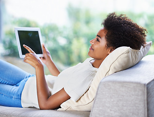 Image showing Tablet, smile and relax woman on sofa, lying down and resting in home living room. Technology, touch screen and happy African woman with afro, couch and social media online for internet communication