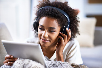 Image showing Tablet, headphone and smile for happy woman, lounge and streaming or movies for entertainment. Relax, weekend and technology for social media, communication and online scrolling for African female
