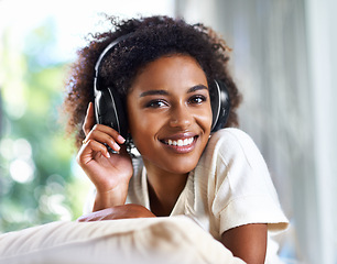 Image showing Portrait, music and smile with black woman in living room of home to relax on sofa for weekend time off. Face, streaming and headphones with happy young person on pillow in apartment for break