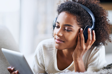 Image showing Headphones, tablet and relax woman in home lounge, streaming and movies for entertainment. Relax, weekend and technology for social media, communication and online scrolling for happy African female