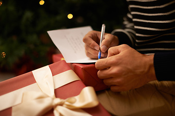 Image showing Writing, hands and man with card and gift for Christmas event or party at home for family. Celebration, paper and closeup of male person with pen for letter with present boxes for festive holiday.