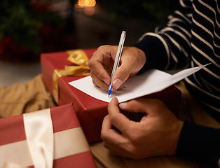 Image showing Pen, hands and man with card and gift for Christmas event or party at home for family. Celebration, paper and closeup of male person writing letter with present boxes for xmas festive holiday.