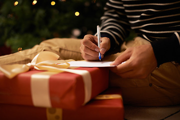 Image showing Pen, hands and man with card and present for Christmas event or party at home for family. Celebration, paper and closeup of male person writing letter with gift boxes for xmas festive holiday.