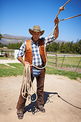 Image showing Cowboy, ranch and farmer in outdoor, sun and straps for wrangler and Texas lasso at stable. Mature man, wild west and summer in agriculture, hat and male person with rope in farm job and environment