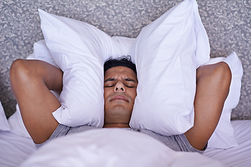 Image showing Man, noise or insomnia in bedroom to rest, tired or cover ears with pillow for crisis of loud issue. Person, frustrated and mad for sound or sleep problem, anxiety and headache or stress in home