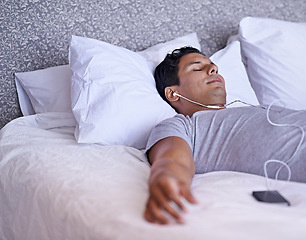 Image showing Man, music or sleeping in bed in morning, tired or peace with audio podcast or audiobook on soft mattress. Calm person, dream or relax by cellphone for online meditation, happy or listening to radio