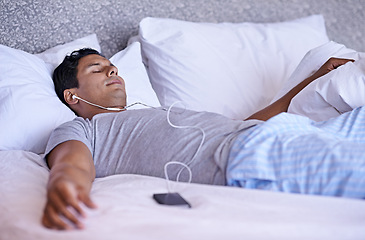 Image showing Man, music and cellphone in bed to relax, tired and audio podcast or audiobook for peace on weekend. Calm person, dream and rest on mobile for online meditation, happy and listening to radio in home