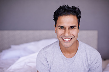 Image showing Man, happy and relax in bedroom in portrait, wellness and confident on morning vacation on home. Young person, smile face and healthy on break on lazy weekend, pyjamas and calm on bed in apartment