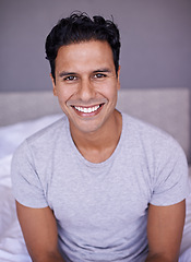 Image showing Man, happy and wellness in bedroom in portrait, peace and confident on morning vacation on home. Young person, smile face and healthy on break on lazy weekend, pyjamas and rest on bed in apartment