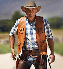 Image showing Portrait, serious cowboy and man at farm in the rural countryside to draw gun in Texas. Ranch, confidence and male person in western hat outdoor in casual clothes in nature with pistol or revolver