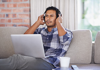 Image showing Man, laptop and living room with home, headset and internet for relax and streaming. Indian person, web and tech with house, lounge or apartment for listen to music and connectivity with subscription