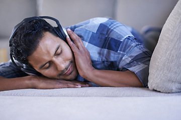 Image showing Man, headphones and relax with song on couch, nap and streaming radio for music or sound. Male person, home and lying on sofa for peace, comfortable and calm playlist on weekend for sleep or meditate