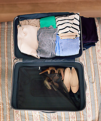 Image showing Travel, luggage and clothes in suitcase for holiday or vacation packing in bedroom from above. Adventure, bag and journey with clothing on bed in apartment, hotel or lodge for weekend getaway