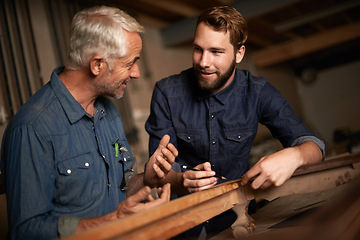 Image showing Carpenter, mentor and furniture building in workshop, learning and talking in small business factory. Smile, happy and teaching of apprentice, professional and discussion of technique and skills