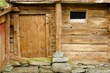 Image showing Rustic wooden barn wall with weathered door and stone foundation