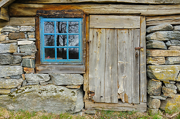 Image showing Rustic charm of a weathered wooden cabin with stone foundation a