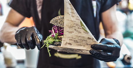 Image showing Chef serving vegetarian salmon burgers outdoor on open kitchen, odprta kuhna, international food festival event. Street food being served on a food stall.