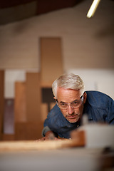 Image showing Carpenter, mature man and working with wood in workplace of workshop as construction worker in company. Employee, male person and professional thinking with glasses for safety in garage and shop