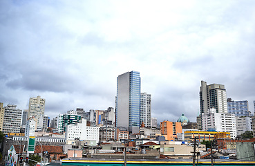 Image showing Cityscape, skyline and buildings in urban architecture with development, expansion and clouds in town. City, metro and skyscraper on road, fog or winter morning on location with dark sky in Sao Paulo