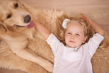 Image showing Girl, dog and relax in portrait for bonding, care and pet for support on floor of living room in home. Child, golden retriever and stroke a puppy in apartment, top view and companion in childhood