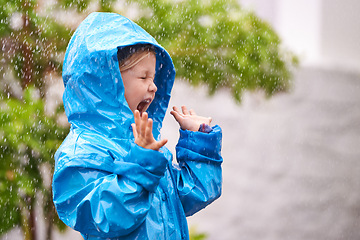 Image showing Young girl, rain and playing outside in winter, raincoat and playful in the water. Joyful, laughing and happy child in cold weather and raindrops, screaming toddler and excited in backyard of home